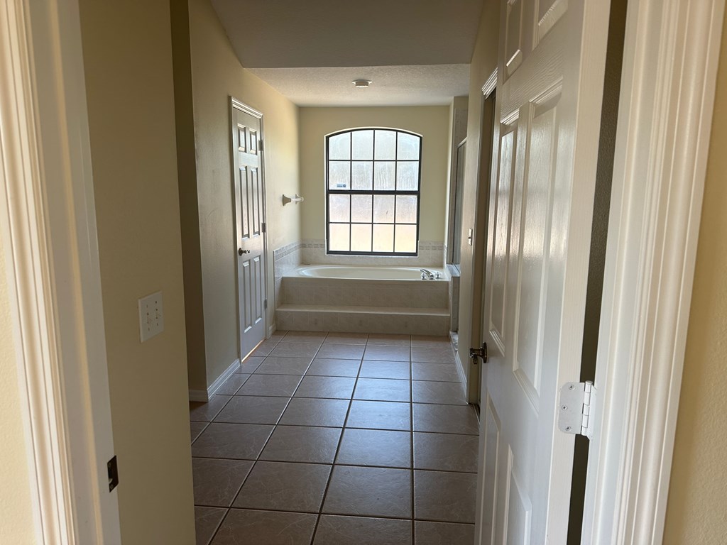 A hallway with a window and tiled floor.