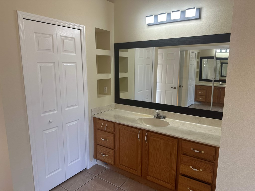 A bathroom with a white door, a sink, and a mirror.