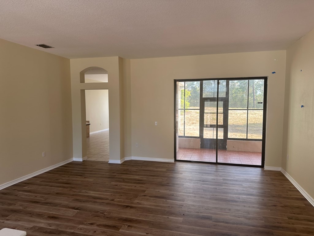 A room with wooden floors and a sliding glass door leading to a balcony.