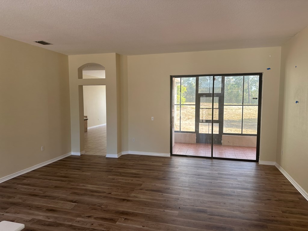 A room with wooden flooring and a sliding glass door leading to a balcony.