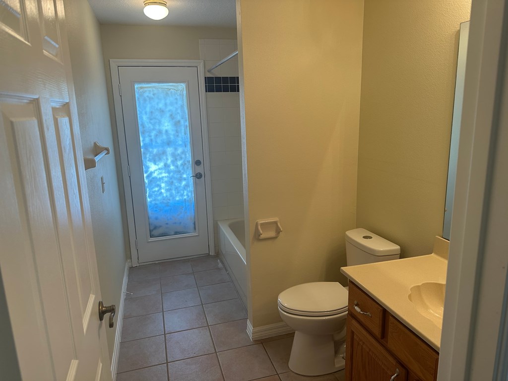A bathroom with a toilet, sink, and a window.