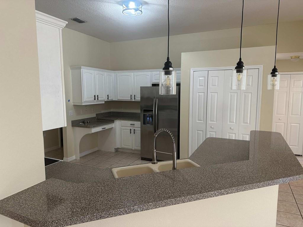 A kitchen with granite countertops and white cabinets.