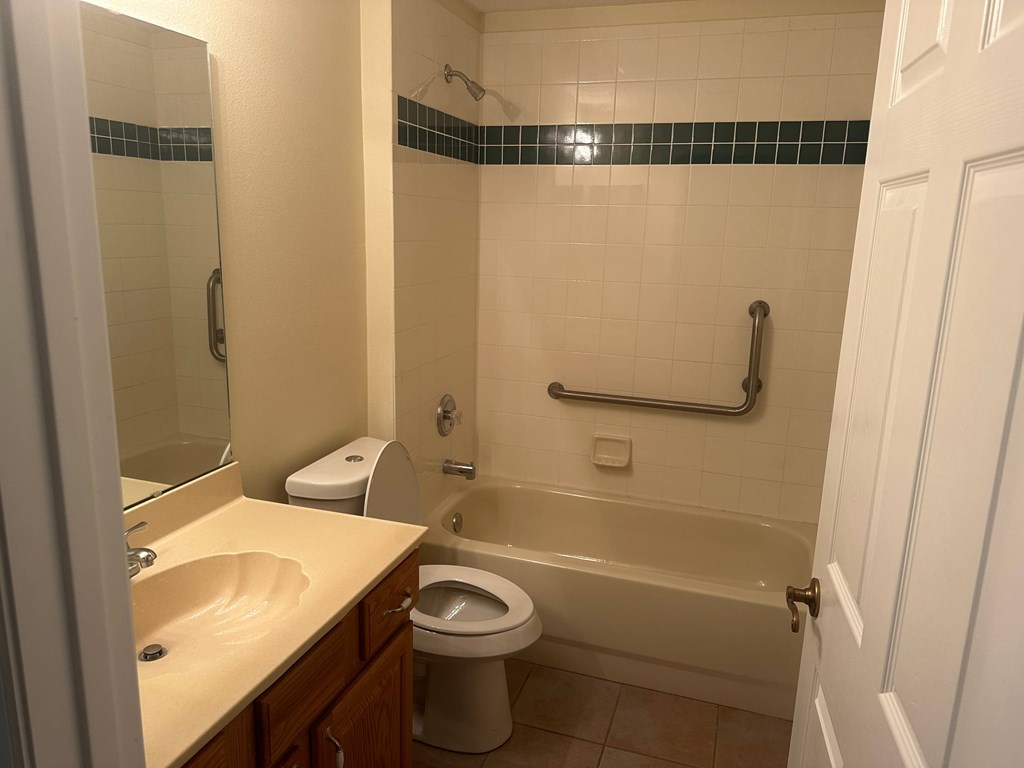 A white toilet is in a bathroom with a white tub.