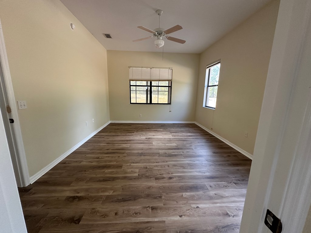 A room with wooden flooring and a ceiling fan.