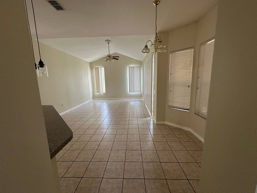 A spacious room with tiled flooring and a ceiling fan.