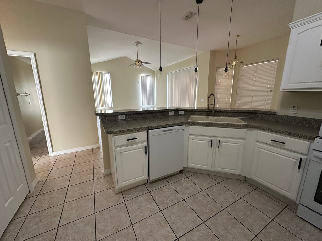 A kitchen with white cabinets and a tiled floor.