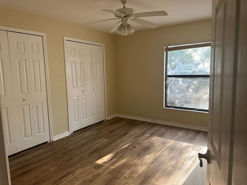 A room with a ceiling fan and two doors.