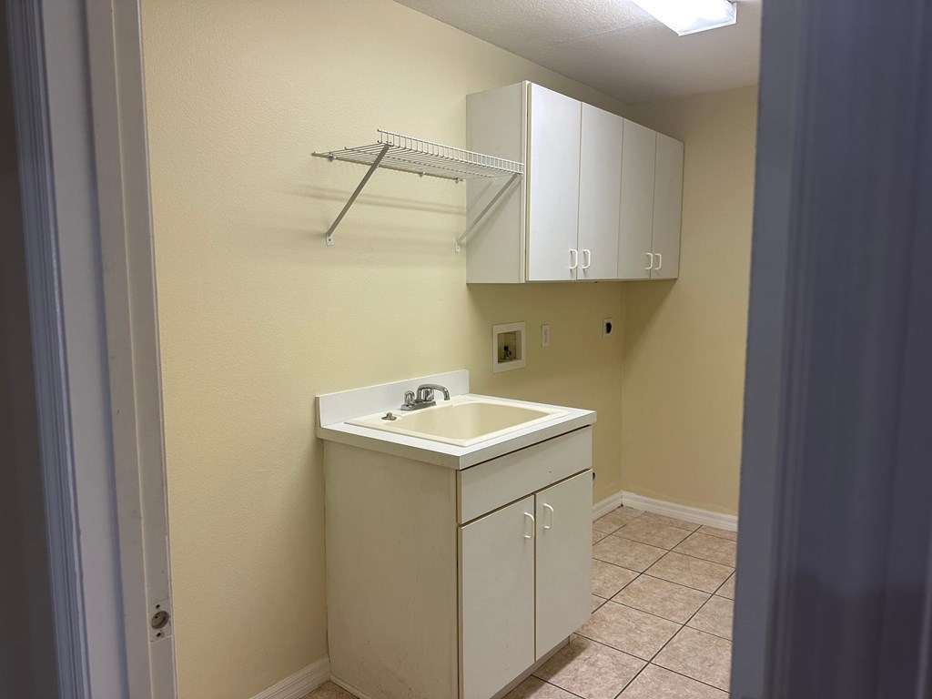 A small white kitchen with a sink and cabinets.