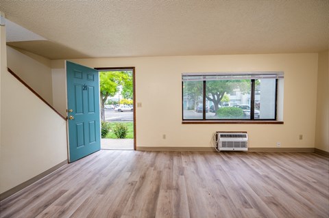 A room with a blue door and a window with a view of trees and a building outside.