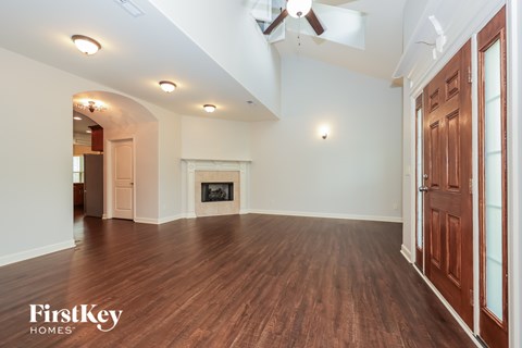 A spacious room with wood flooring and a fireplace.