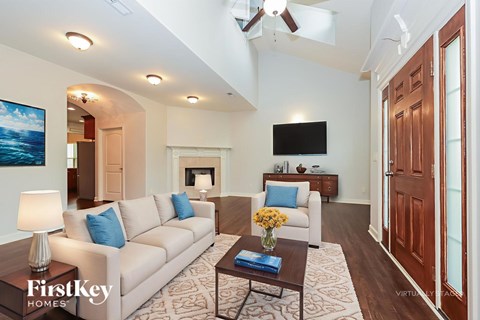 A well-lit living room with a couch, coffee table, and television.