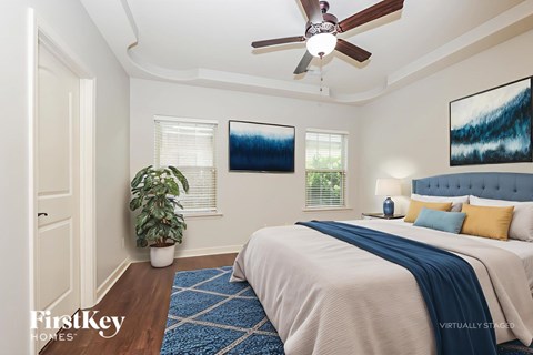A bedroom with a bed, a ceiling fan, and a potted plant.