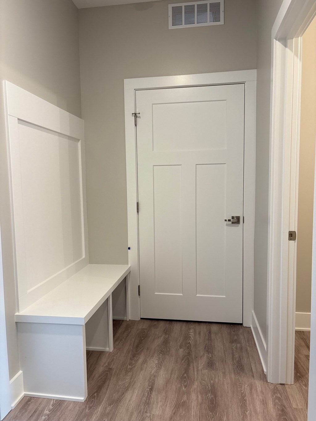A white door with a white bench to the left of it.