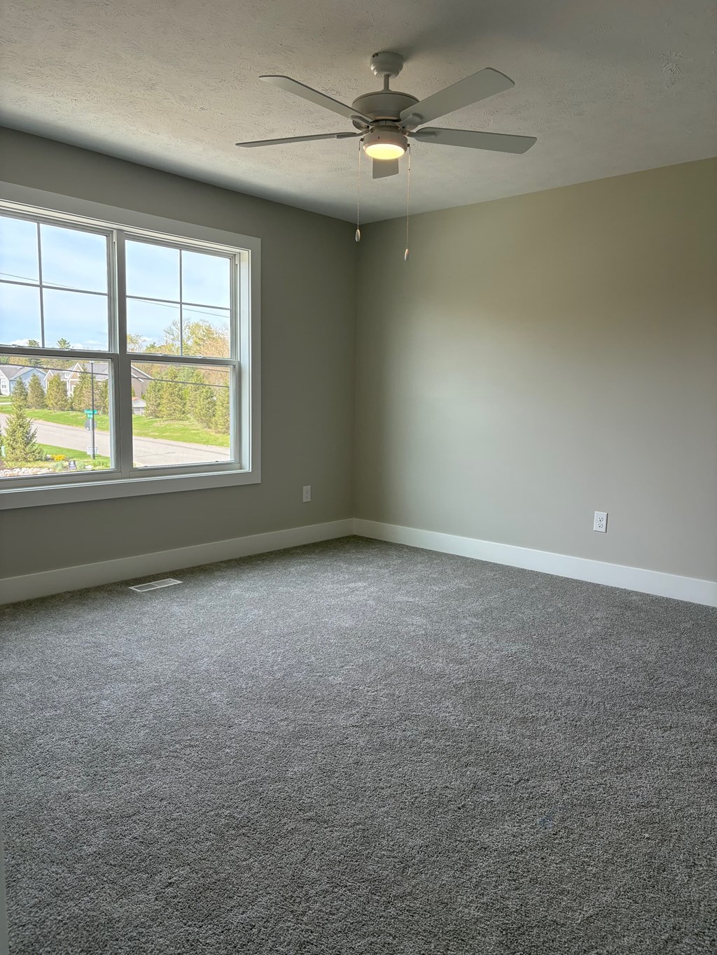 A room with a ceiling fan and a large window.