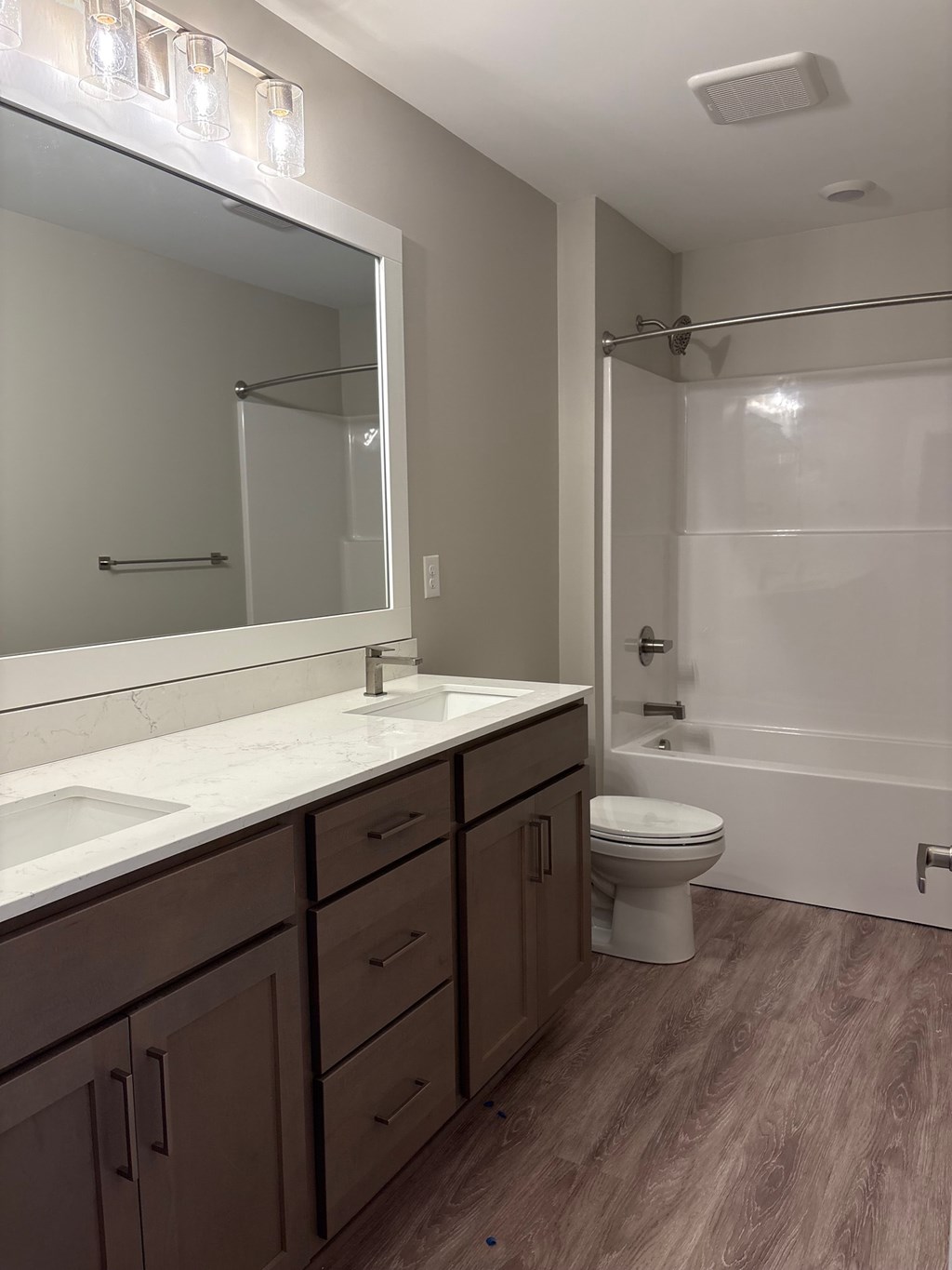 A bathroom with a white sink, brown cabinets, and a white toilet.