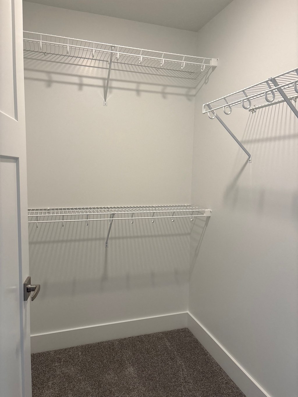 Empty white walk in closet with shelves.