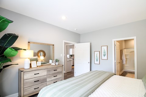 A bedroom with a bed, dresser, mirror, and two framed pictures on the wall.