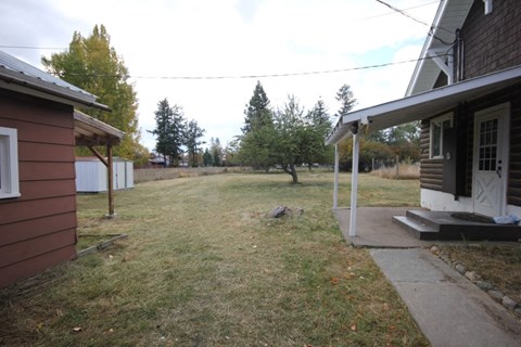 A house with a brown exterior and a white door is surrounded by a grassy area.