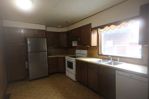 A kitchen with brown cabinets and a stainless steel refrigerator.