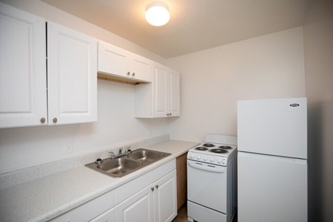 A kitchen with white cabinets and appliances.