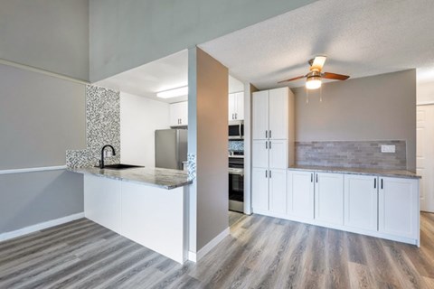 A kitchen with white cabinets and a grey countertop.