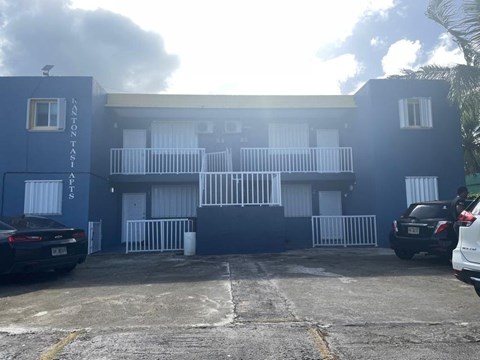 A parking lot in front of a blue building with the name "Lanon Tailor" on it.