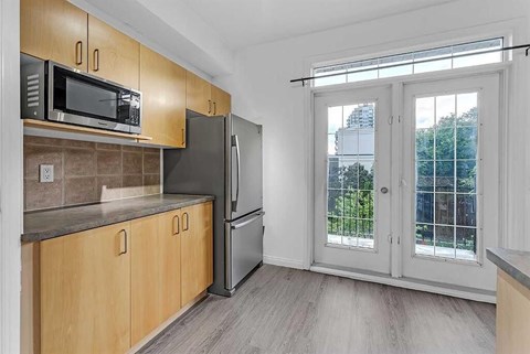 A kitchen with wooden cabinets and a black refrigerator.