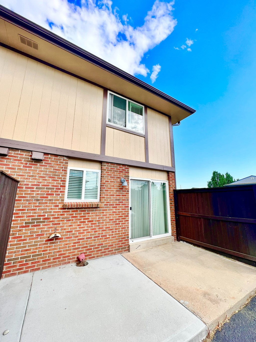 A house with a brown brick wall and a green door.