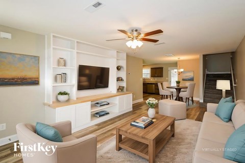 A living room with a beige couch, a wooden coffee table, and a painting on the wall.