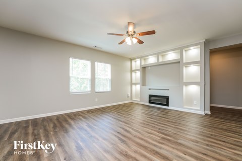 A spacious room with a fireplace and a ceiling fan.