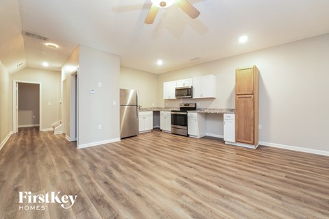 A spacious kitchen with wooden floors and white walls.