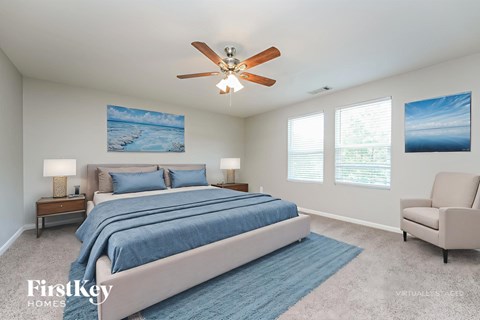A bedroom with a large bed, a ceiling fan, and two pictures on the wall.