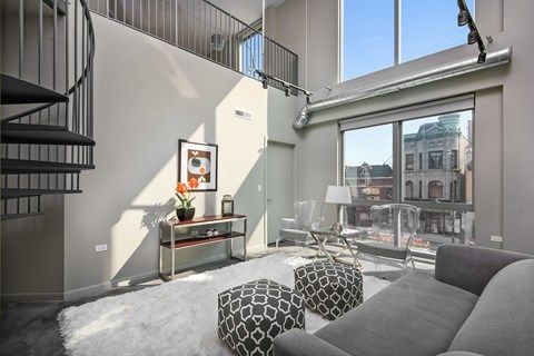 A living room with a grey sofa and a black and white ottoman.