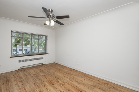 A room with a ceiling fan and a window with a view of a building outside.
