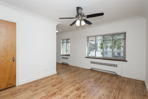 A room with a ceiling fan and wooden flooring.