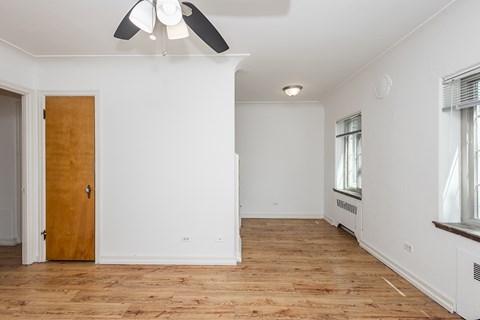 A room with a ceiling fan and wooden flooring.