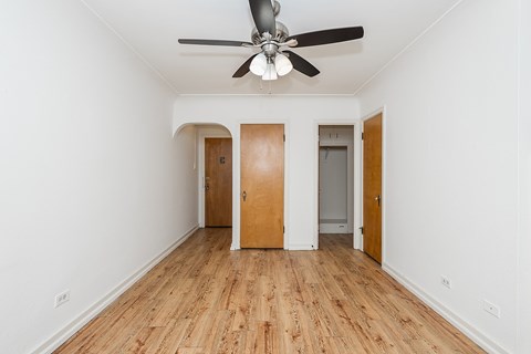 A room with a ceiling fan and wooden floors.