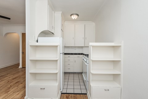 A kitchen with white cabinets and a black and white tiled floor.