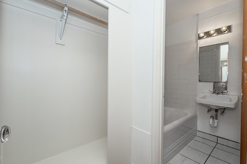 A white bathroom with a tub, sink, and mirror.