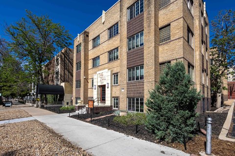 A large brick building with a black awning and a tree in front.