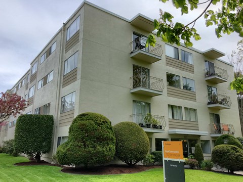 Apartment building with green bushes in front.