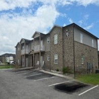 Apartment building with a parking lot in front.
