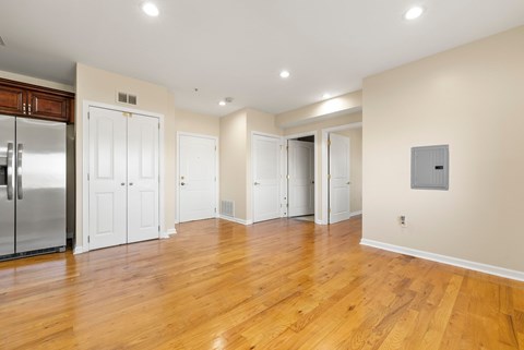 A kitchen with a refrigerator and wooden floors.