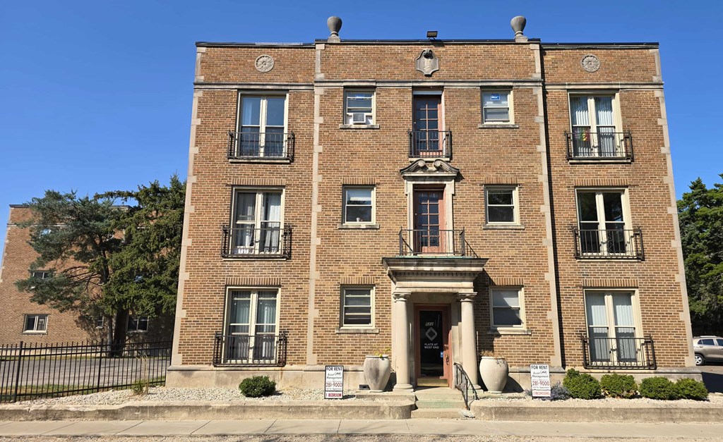 A large brick building with a black iron fence in front.