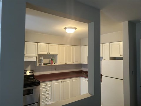 A kitchen with white cabinets and a stove top oven.