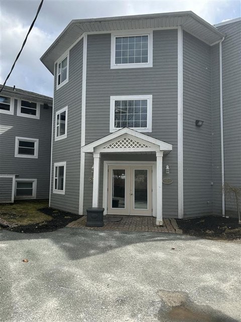 A grey house with a white door and windows.