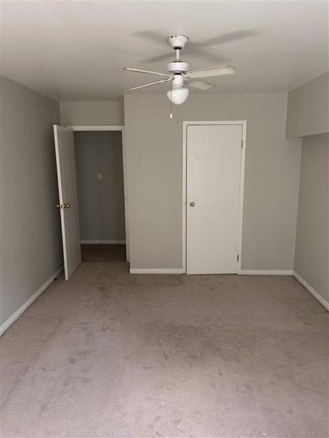 A room with a ceiling fan and two doors.