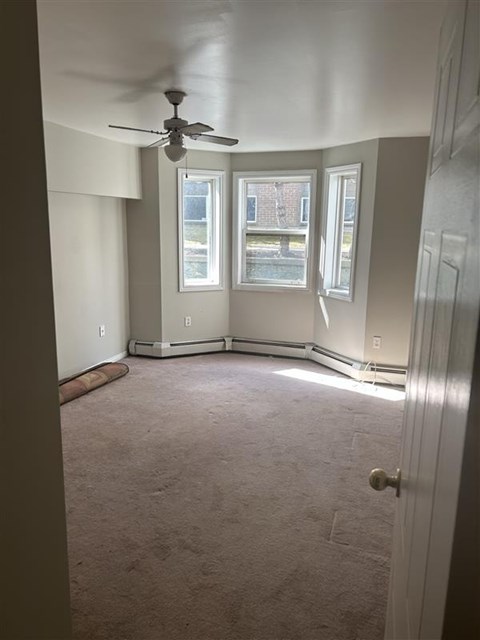 A room with a ceiling fan and two windows.