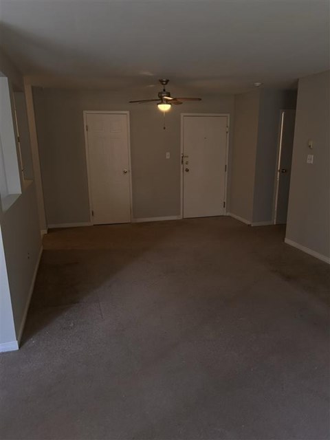 A room with a ceiling fan and three doors.