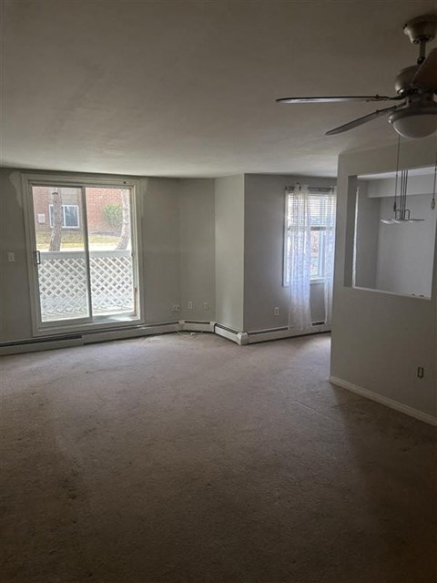 A room with a fan, a window with a lattice design, and a door leading to a balcony.